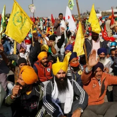 Determined farmers holding signs and flags during a protest gathering.