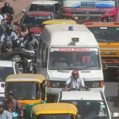 mbulance stuck in traffic due to obstruction, police officer issuing challan.