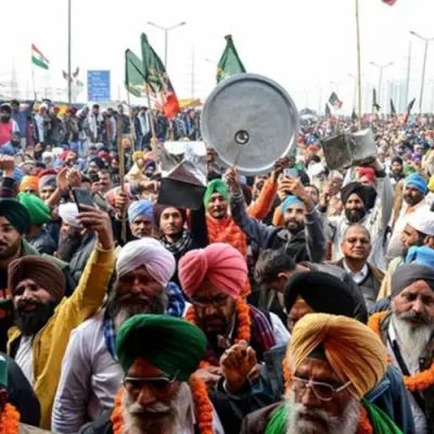 Farmers' protest with tractors parked on highway, protesters holding signs.