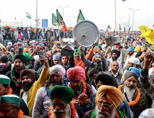 Farmers' protest with tractors parked on highway, protesters holding signs.