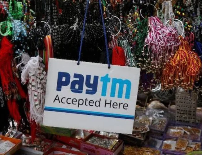 A line graph showing a downward trend, symbolizing the decline in Paytm's stock price. Regulatory restrictions and leadership changes are depicted as icons beside the graph