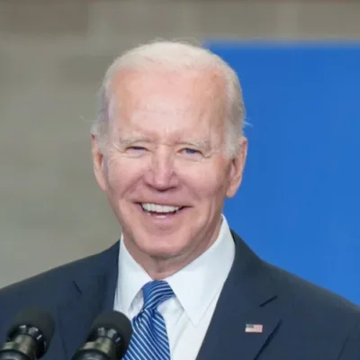 President Joe Biden smiles and points in a TikTok video, surrounded by young people and holding a football.