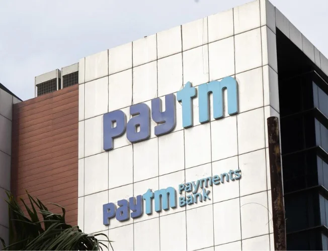 Paytm stock chart with downward trend and RBI logo, symbolizing impact of regulations.