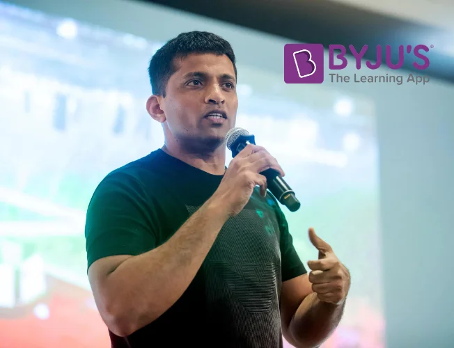 BYJU’S logo on a digital tablet with a valuation chart in the background.