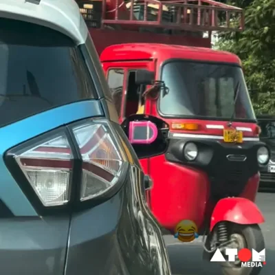 The image depicts a car parked at a traffic signal in Maharashtra, with a broken side mirror replaced by a plastic mirror. This inventive solution showcases the concept of 'jugaad', or innovative improvisation, prevalent in Indian culture.