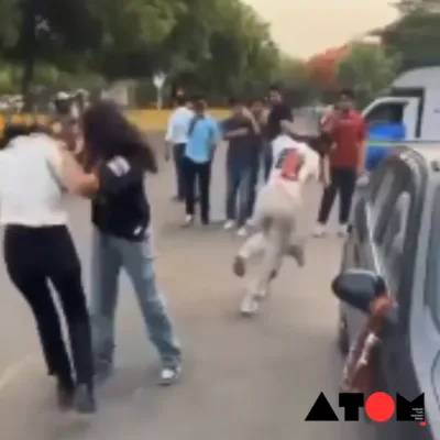 Two girls engaged in a physical altercation on a street in Noida, surrounded by bystanders.