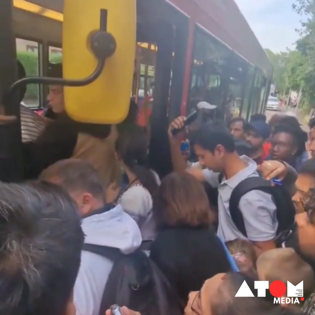 The image shows a crowded bus stop in Ruislip, West London, with a throng of people attempting to board a bus, highlighting the chaotic scene captured in the viral video.