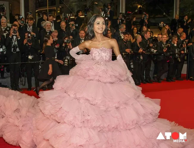 A group of social media influencers posing for photos on the red carpet at the Cannes Film Festival. Some wear designer gowns and tuxedos, while others have more casual attire.