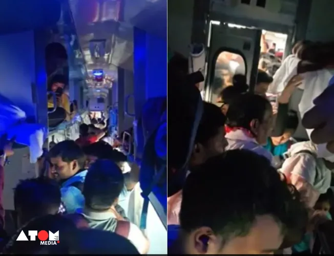 A crowded train compartment in India, with passengers sitting on luggage and overflowing aisles.