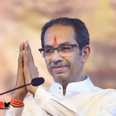 Uddhav Thackeray addressing a crowd with Shiv Sena flag in the background.