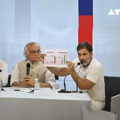 The image depicts Congress leader Rahul Gandhi delivering a speech at a press briefing, where he discusses allegations of a stock market scam and calls for a joint parliamentary committee investigation.